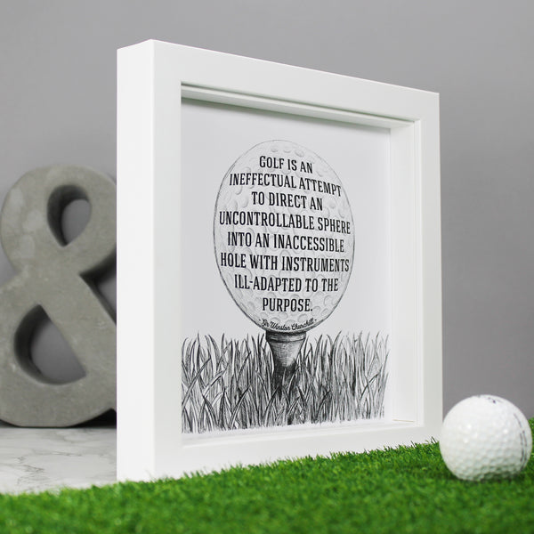 Sir Winston Churchill funny golf quote: Golf is an ineffectual attempt to direct and uncontrollable sphere into an inaccessible hole with instruments ill-adapted to the purpose. Framed illustrated art print gift for golfers. Made by Wit and Wisdom UK. Shown here in a quare white box frame against a grey backdrop at an oblique angle to demonstrate the depth of the box frame.