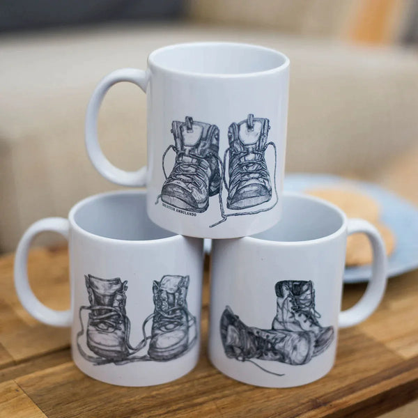 Three mugs stacked showing the Solvitur Ambulando Walking Boot Mugs range of three different walking boot illustrations.
