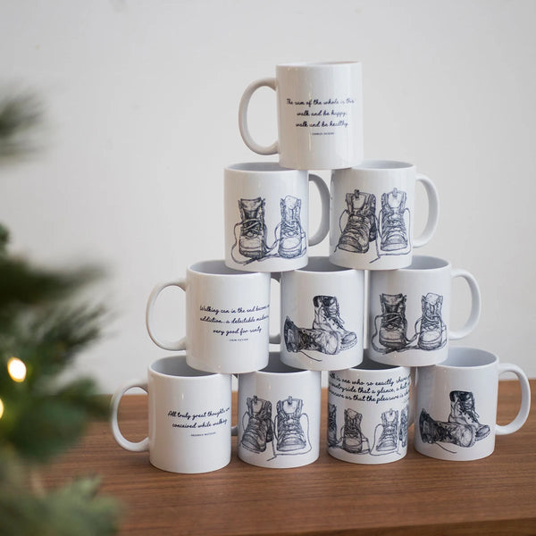 Pyramid of stacked hiking mug range by Wit and Wisdom next to Christmas tree in foreground.