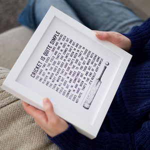 closeup of womans hands holding a framed cricket is quite simple quote art print in a white picture frame