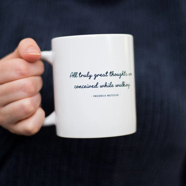 Woman holding a great thoughts walking quote mug designed by Wit and Wisdom.